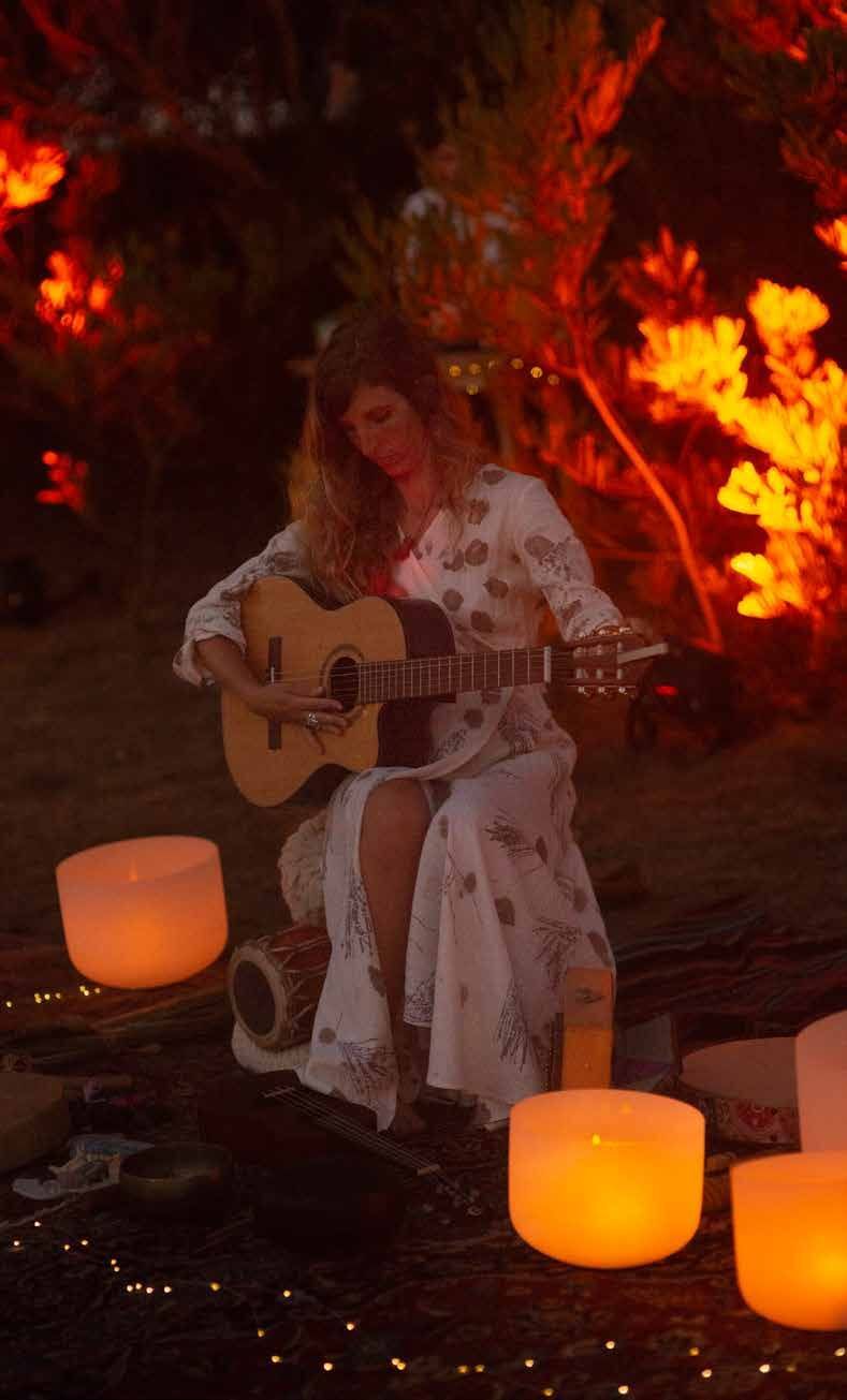 Artista tocando guitarra rodeada de velas en activación nocturna